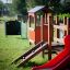 Attrezzature da parco giochi per bambini con scivolo rosso e struttura da arrampicata in legno.