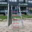 Struttura da gioco in acciaio con reti da arrampicata installate in un parco giochi sabbioso.