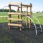 Sherwood wooden playhouse con struttura da arrampicata e scala su un parco giochi erboso.