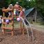 Bambini che giocano su Sherwood wooden playhouse in un parco.
