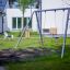 Silver Double Swing in un parco giochi circondato da erba verde e attrezzature da gioco.