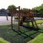 Serengeti wooden playhouse nel parco giochi con reti da arrampicata e scivolo.