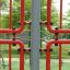 Struttura da arrampicata rossa delle attrezzature da parco giochi Shea in un parco verde.