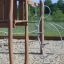 Una struttura da parco giochi in legno con elementi metallici per arrampicarsi su una superficie sabbiosa della serie Alv.