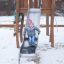 Bambino che scivola su uno scivolo del parco giochi Alv in inverno.