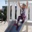 Bambina che scivola giù dallo scivolo Nature Ship Sandbox, wooden playhouse