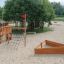 Nature Ship Sandbox, wooden playhouse in un parco giochi sabbioso con alberi tutt'intorno.