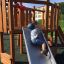 Bambino che gioca sullo scivolo Nature Ship Sandbox, wooden playhouse.