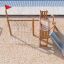 Nature Ship Sandbox, wooden playhouse con scivolo e rete da arrampicata su un parco giochi sabbioso.