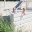 Due bambine che giocano in un Nature Ship Sandbox, wooden playhouse su un parco giochi sabbioso.