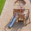 Casetta da gioco in legno Nature Ship Sandbox con scivolo in un parco giochi.