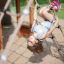 Bambino che gioca sulla rete di corda del Nature Ship Sandbox, wooden playhouse.