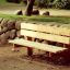 Larchwood Bench collocato in un parco accanto a un muro di pietra.