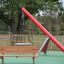Larchwood Bench in un parco giochi con un'altalena e uno scivolo sullo sfondo'