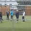 Bambini che giocano a calcio sul campo sportivo Goal recintato da una rete metallica.