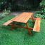 Larchwood Table & Bench all'aperto sull'erba verde.