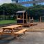 Larchwood Table & Bench in un parco giochi vicino a una sabbiera e a una struttura ludica.