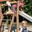 Bambini che giocano su uno scivolo da parco giochi in legno Bergila.