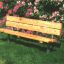 Panchina in legno con struttura in acciaio in un giardino con fiori in fiore.