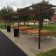 Area salotto all'aperto con Table, Steel Construction e panche sotto una pergola in metallo.