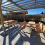 Set da esterno in legno Table & Bench sotto una pergola in legno in un'area pavimentata.