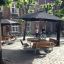 Set Table & Bench Quadro in un cortile sotto grandi ombrelloni neri.