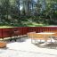 Table & Bench Quadro in un ambiente esterno panoramico con una recinzione rossa e uno sfondo di foresta verde.