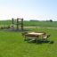 Table & Bench Quadro in un'area verde del parco con un parco giochi sullo sfondo.