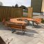 Set in legno School Table & Bench disposto in configurazione esagonale in un'area esterna pavimentata.