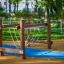 Attrezzatura da parco giochi 'Kongo' con telai in legno e corde sospese in un contesto di parco.