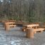Table & Bench Nature in un parco con tavoli e panche in legno.