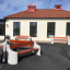 Panchine da esterno Dona con seduta in legno e supporti in cemento davanti a un edificio.
