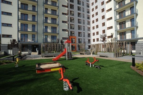 Tappeto antitrauma da 45 mm con erba artificiale installato in un moderno parco giochi con varie attrezzature da gioco