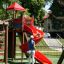 Bambini che giocano su uno scivolo a spirale rosso in un parco giochi.