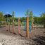 Attrezzatura da parco giochi all'aperto Triple Somersault Nature in un giardino con alberi e cielo aperto.