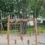 Casetta da gioco in legno Lianes in un parco giochi con reti da arrampicata e pali di legno