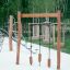 Corde di equilibrio del parco giochi in legno Lianes con blocchi di appoggio su una superficie sabbiosa.