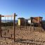 Casetta in legno Lianes in un parco giochi sulla spiaggia con attrezzature per arrampicata e scivolo.