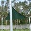 Sun Shade Triangle 3x3x3 Atlantis (Metal) installato in un'area erbosa con alberi alti sullo sfondo