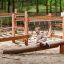Bambino che gioca su Sahara trave di equilibrio in legno in un parco giochi nel bosco