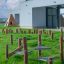 Attrezzatura da gioco in legno Gobi su un prato verde davanti a un moderno edificio scolastico.