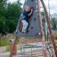 Un bambino che si arrampica su Tipi II climbing net in un parco giochi.
