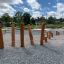 Percorso di travi di equilibrio in legno Cape Code su parco giochi in ghiaia con sfondo di erba verde.