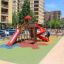 Parco giochi con superficie colorata Wetpour 100 e scivoli in area urbana.