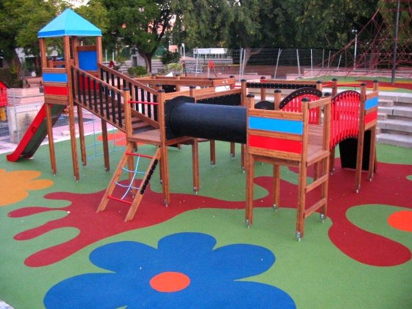 Struttura da parco giochi in legno su pavimentazione di sicurezza colorata Wetpour 100.