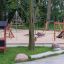 Set da parco giochi Playhouse Nature con strutture da arrampicata e scivoli in un parco.