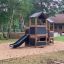 Knight's Castle Nature playhouse with slide in un parco giochi nel bosco