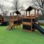 Knight's Castle Nature playhouse with slide in un contesto di parco giochi'