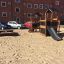 Knight's Castle Nature playhouse with slide in un'area giochi sabbiosa con un edificio residenziale in mattoni