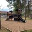 Knight's Castle Nature playhouse with slide in un'area giochi boscosa.
